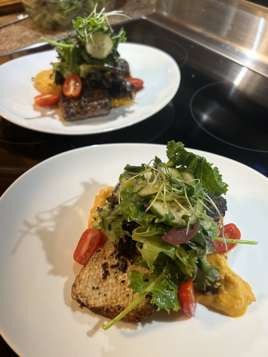 Two plated courses with dressed greens, prepared in a home kitchen by a ChefsPrep private chef